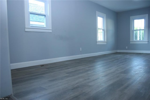 spare room with dark hardwood / wood-style flooring and a wealth of natural light