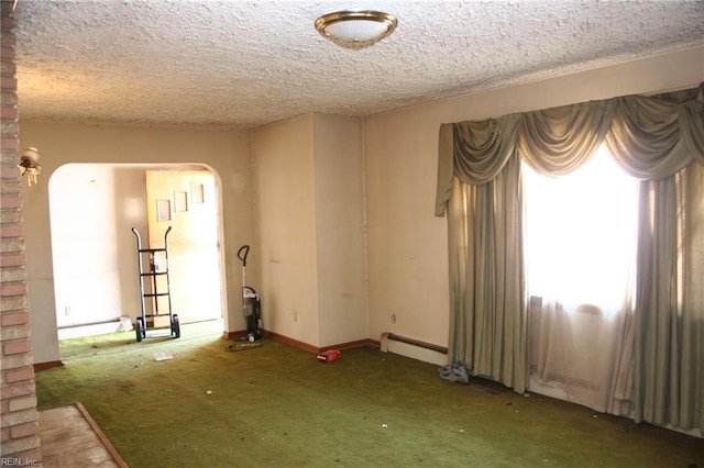 empty room featuring carpet, a textured ceiling, and a baseboard heating unit