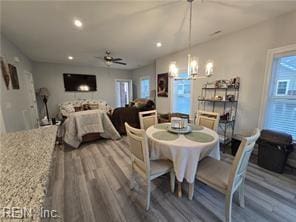 dining area featuring hardwood / wood-style flooring and ceiling fan with notable chandelier