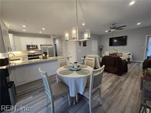 dining area featuring sink, dark wood-type flooring, and ceiling fan with notable chandelier