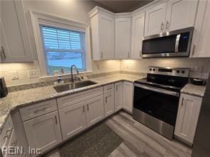 kitchen with light stone countertops, tasteful backsplash, stainless steel appliances, sink, and white cabinetry