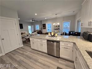 kitchen with light stone countertops, stainless steel dishwasher, light hardwood / wood-style floors, white cabinets, and ceiling fan with notable chandelier