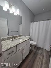 bathroom featuring curtained shower, vanity, wood-type flooring, and toilet