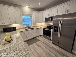 kitchen featuring light stone counters, sink, white cabinets, and appliances with stainless steel finishes