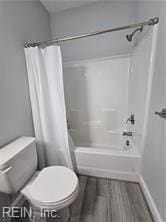 bathroom featuring hardwood / wood-style floors, toilet, and shower / bathtub combination with curtain