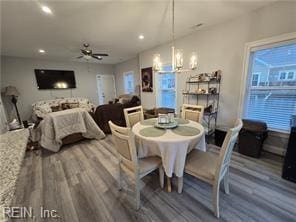 dining room with ceiling fan with notable chandelier and wood-type flooring