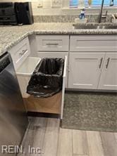 kitchen featuring white cabinets, hardwood / wood-style flooring, light stone counters, and sink