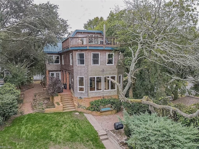 rear view of property featuring a balcony and a lawn