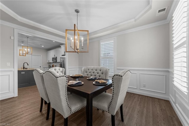 dining area featuring sink, dark hardwood / wood-style flooring, a notable chandelier, and ornamental molding