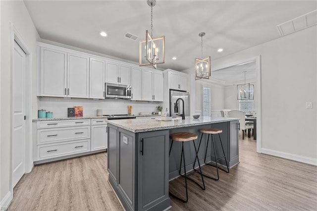 kitchen featuring white cabinetry, a center island with sink, and stainless steel appliances