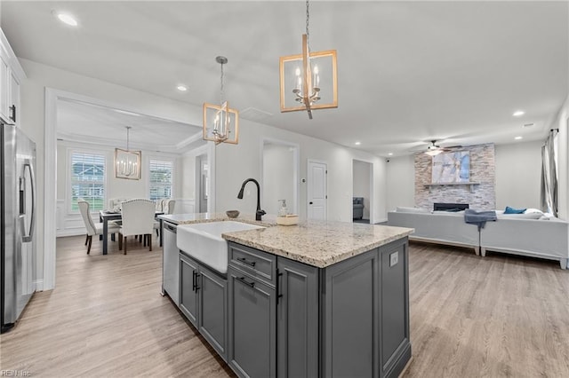 kitchen with stainless steel appliances, gray cabinets, hanging light fixtures, and light hardwood / wood-style floors