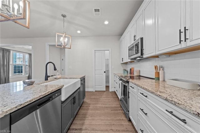 kitchen with sink, stainless steel appliances, a chandelier, light hardwood / wood-style floors, and white cabinets