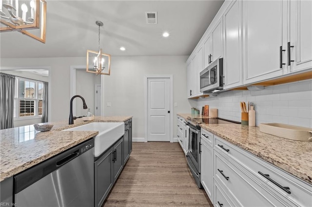 kitchen with sink, decorative light fixtures, light hardwood / wood-style floors, white cabinetry, and stainless steel appliances