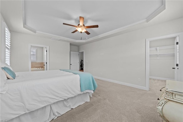 carpeted bedroom with a walk in closet, a raised ceiling, a closet, and ceiling fan