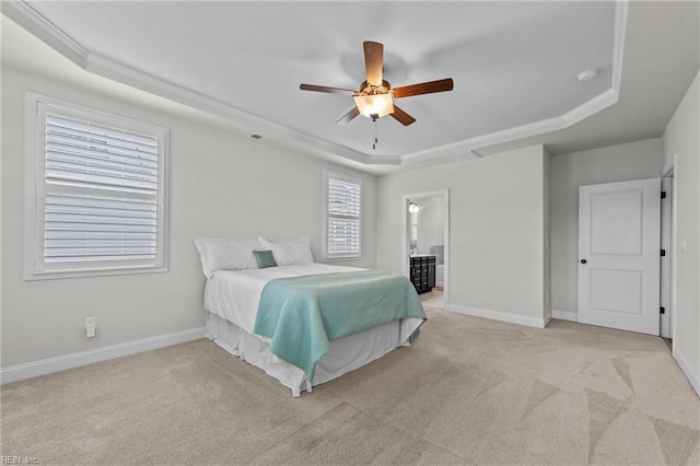 carpeted bedroom with ceiling fan, a raised ceiling, and ensuite bath