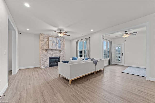 living room with ceiling fan, a fireplace, and light hardwood / wood-style floors