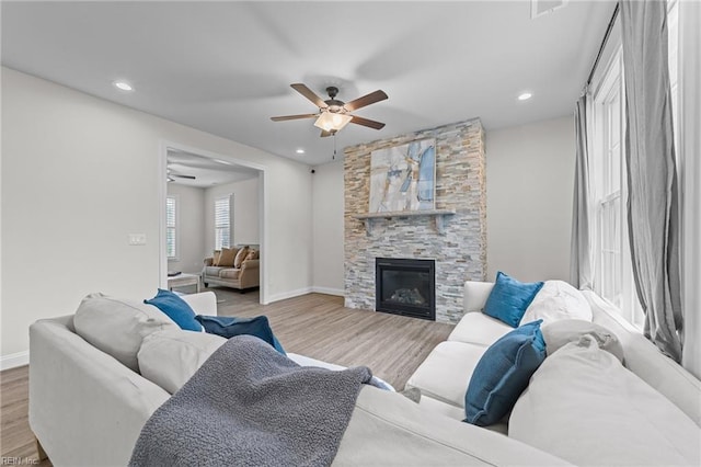 living room featuring ceiling fan, a fireplace, and light hardwood / wood-style flooring