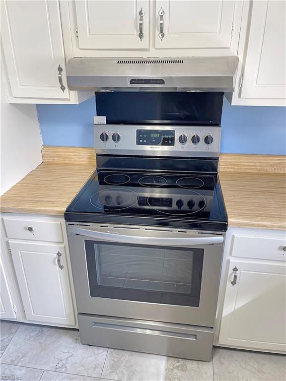 kitchen featuring white cabinets, stainless steel electric range oven, and range hood