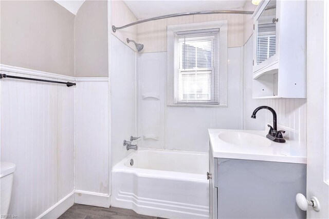 full bathroom featuring wood-type flooring, vaulted ceiling,  shower combination, toilet, and vanity