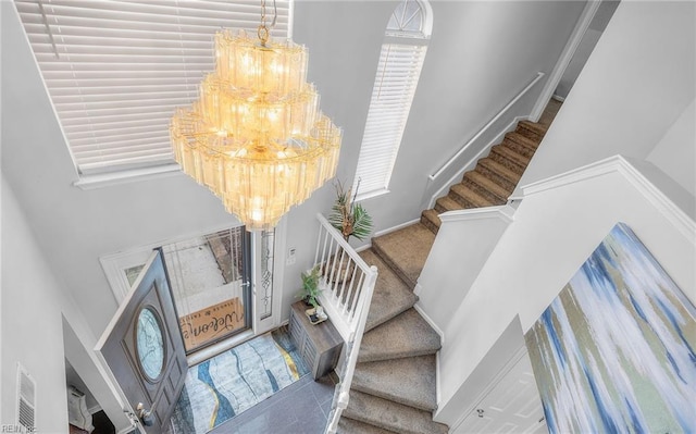 staircase featuring a healthy amount of sunlight, carpet, and a chandelier