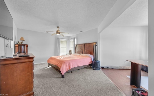 carpeted bedroom featuring ceiling fan and a textured ceiling