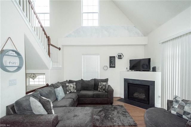 living room with a wealth of natural light, high vaulted ceiling, and hardwood / wood-style flooring