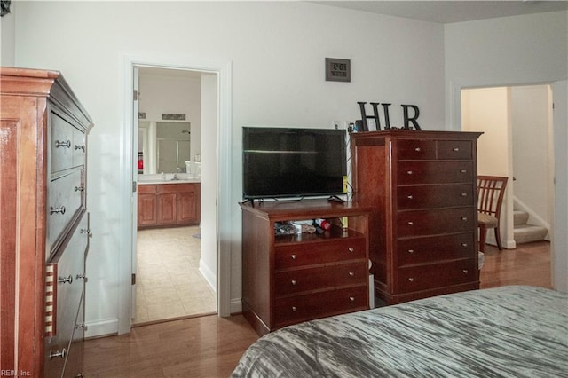 bedroom with wood-type flooring, ensuite bath, and sink