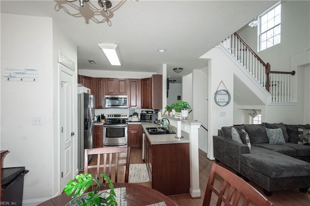 kitchen featuring sink, stainless steel appliances, kitchen peninsula, a chandelier, and wood-type flooring