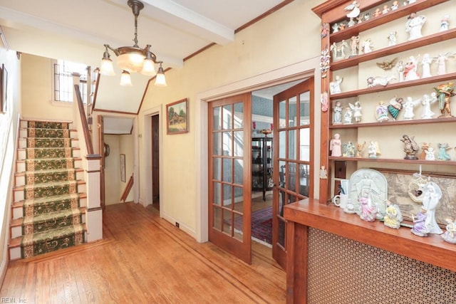 interior space featuring a chandelier, beam ceiling, light hardwood / wood-style floors, and french doors