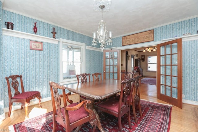 dining area with a notable chandelier, ornamental molding, and french doors