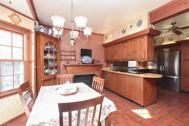 kitchen with appliances with stainless steel finishes, ornamental molding, ceiling fan with notable chandelier, dark tile patterned flooring, and hanging light fixtures