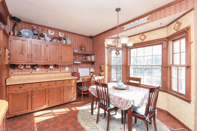 dining room featuring dark tile patterned flooring, crown molding, and an inviting chandelier