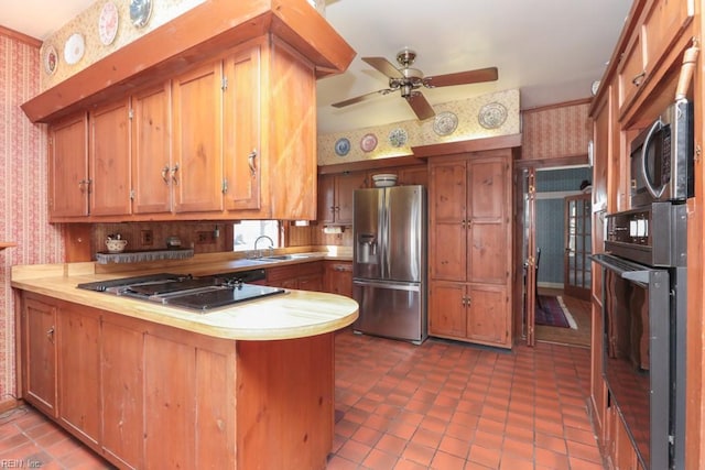 kitchen featuring black appliances, dark tile patterned flooring, sink, ceiling fan, and kitchen peninsula