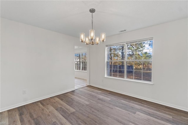 unfurnished dining area with wood-type flooring and an inviting chandelier