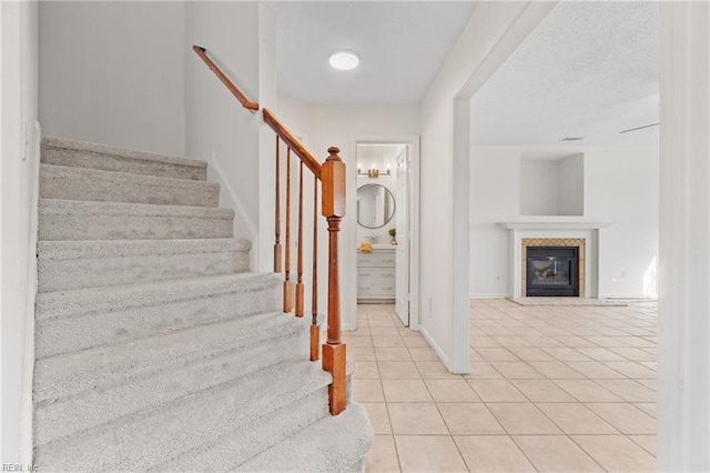 stairway featuring a tiled fireplace and tile patterned flooring