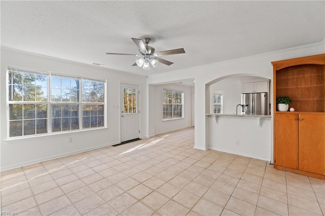 unfurnished living room featuring ceiling fan, a healthy amount of sunlight, and light tile patterned floors