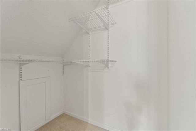 spacious closet with light carpet and vaulted ceiling