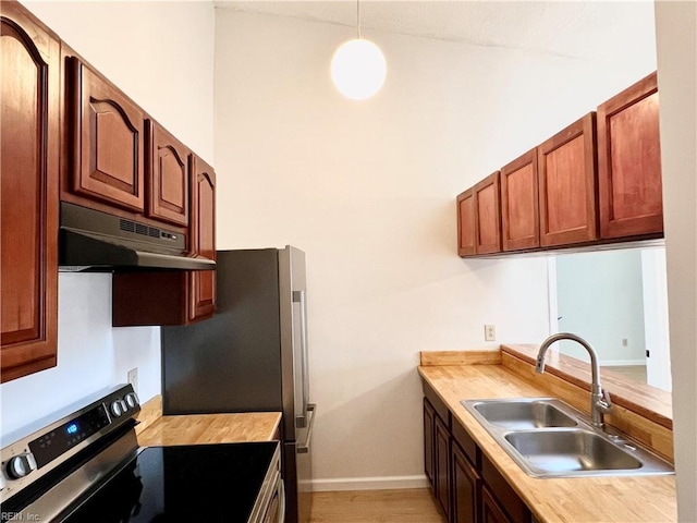 kitchen with wood counters, stainless steel electric stove, sink, hanging light fixtures, and light hardwood / wood-style floors