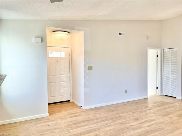 foyer featuring lofted ceiling, a textured ceiling, and light hardwood / wood-style flooring