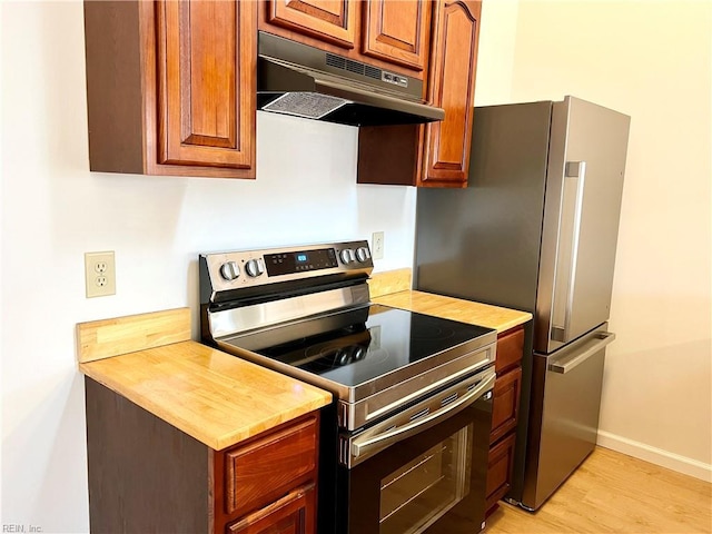 kitchen featuring appliances with stainless steel finishes, light wood-type flooring, and exhaust hood