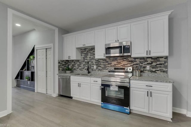 kitchen with white cabinets, appliances with stainless steel finishes, light hardwood / wood-style flooring, and sink