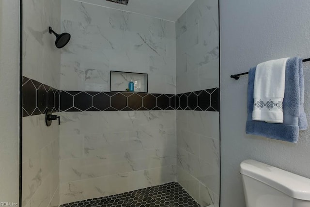 bathroom with tiled shower and toilet