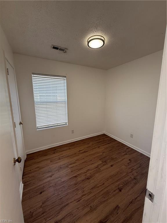 unfurnished room with a textured ceiling and dark wood-type flooring