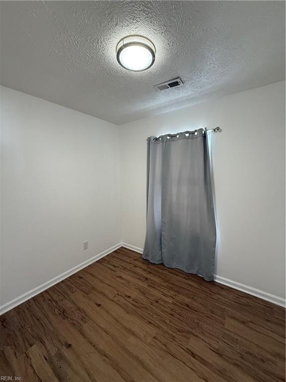 spare room with a textured ceiling and dark wood-type flooring