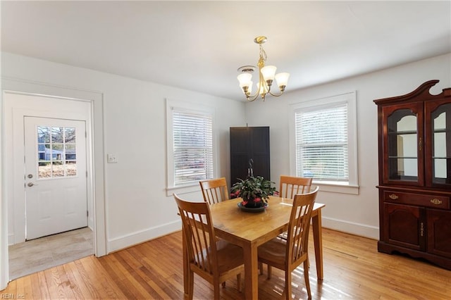 dining space featuring light hardwood / wood-style floors and an inviting chandelier