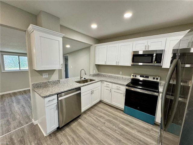 kitchen featuring white cabinets, sink, light wood-type flooring, kitchen peninsula, and stainless steel appliances