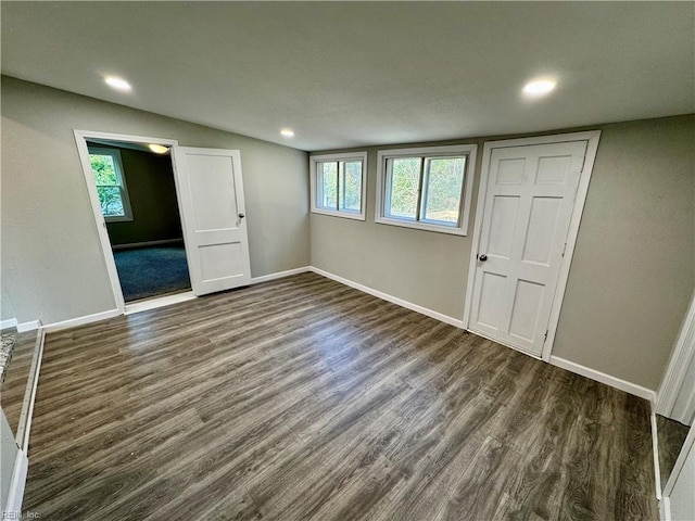 spare room featuring dark hardwood / wood-style flooring, a healthy amount of sunlight, and vaulted ceiling