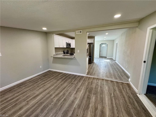 unfurnished living room featuring a textured ceiling, sink, and dark hardwood / wood-style floors