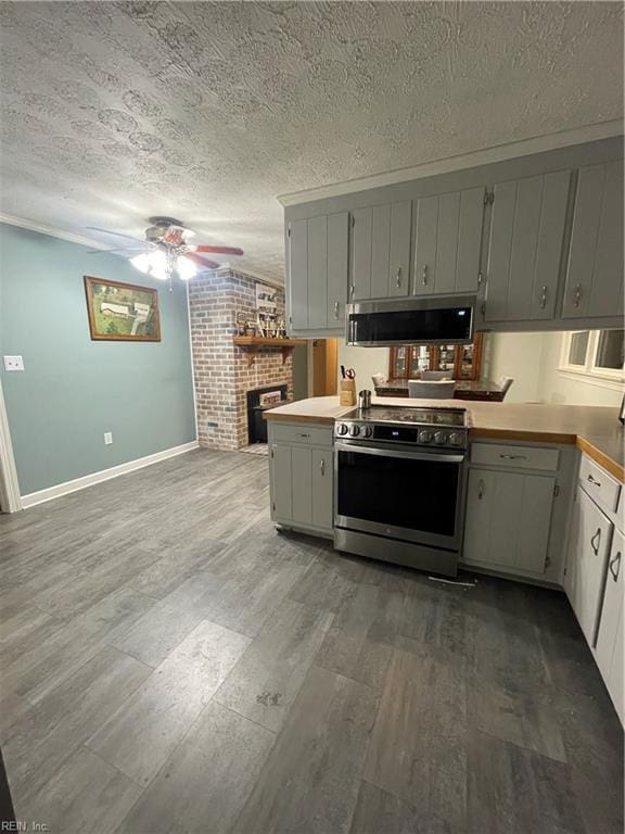 kitchen featuring kitchen peninsula, a brick fireplace, a textured ceiling, stainless steel appliances, and white cabinets