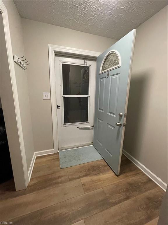 entryway with dark wood-type flooring and a textured ceiling